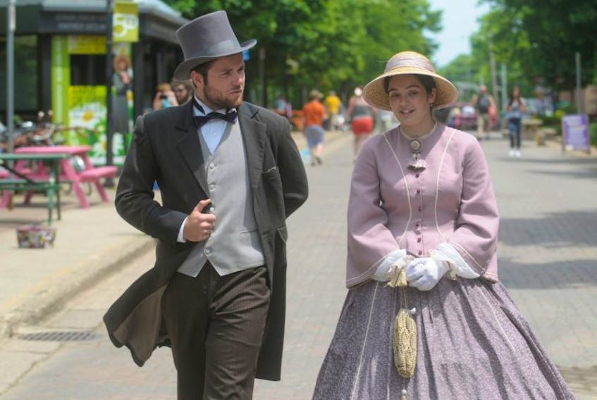 Hector-Louis Langevin, played by Brandon Roy, and Mercy Coles, played by Catherine MacDonald, stroll Victoria Row in full Confederation Player character and costume.