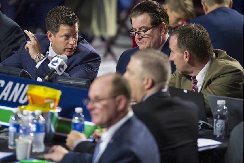 Scouting director Judd Brackett, left, talks to Vancouver Canucks' GM Jim Benning, centre, and AGM John Weisbrod during the 2019 NHL Entry Draft at Rogers Arena in Vancouver. Brackett wanted some conditions before accepting a two-year contract extension from the NHL club, but Benning refused to budge.