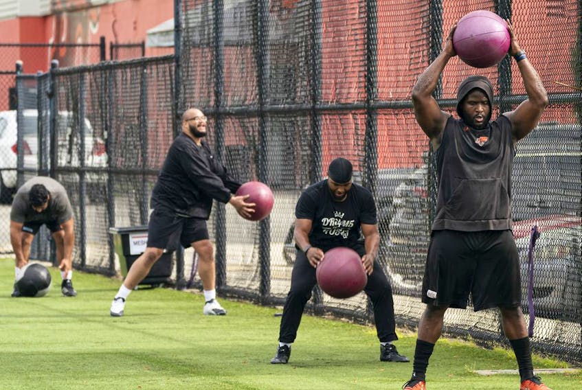 Defensive tackle Claudell Louis, right, a small group of teammates throw medicine balls around during a workout at the B.C. Lions' practice facility in Surrey on Tuesday.