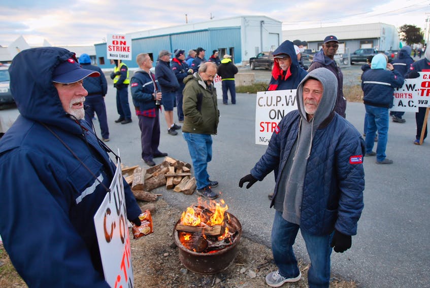 CUPW members try to keep warm during an early-morning shift on the picket line at the Canada Post location at 28 Topple Dr. in Dartmouth on Monday.
