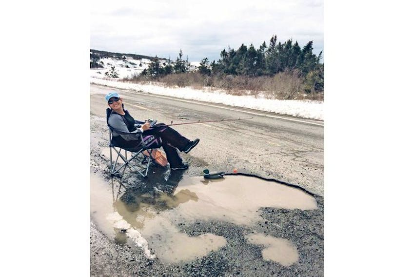 To draw attention to the state of Route 90, paramedic Nicole Yetman-Ryan poses with a fishing pole while seated next to a large pothole. — Submitted photo