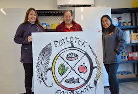 From left, Tahirih Paul, Anita Basque and Mary Susan Lafford hold up the food bank sign at the grand opening of the Potlotek facility on Wednesday. The sign was designed by local artist Mary Lee Johnson, whose work was chosen from 13 other submissions. OSCAR BAKER III • CAPE BRETON POST