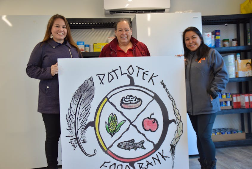 From left, Tahirih Paul, Anita Basque and Mary Susan Lafford hold up the food bank sign at the grand opening of the Potlotek facility on Wednesday. The sign was designed by local artist Mary Lee Johnson, whose work was chosen from 13 other submissions. OSCAR BAKER III • CAPE BRETON POST