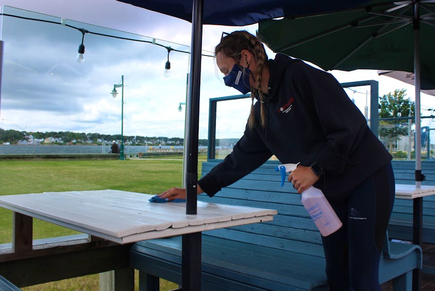 Staff of Portside Beer Garden on Sydney harbour were found preparing for their lunch crowd early Wednesday morning. Among their tasks was cleaning and drying the tables after a rain storm passed over the night before. Kristen Briand, a server at the popular spot, was expecting a busy day. GREG MCNEIL/CAPE BRETON POST