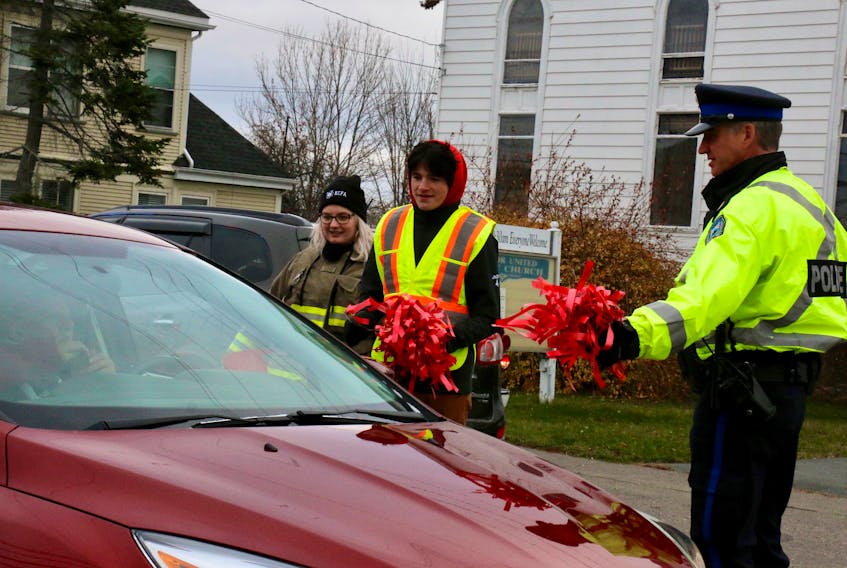 Greenwich firefighter Haley McCraig and MADD Annapolis Valley board member and Avon View High School student Jacob Skanes joined Sgt. Mike Goss, with Kentville Police Service, handing out red ribbons Nov. 18 in Windsor. 