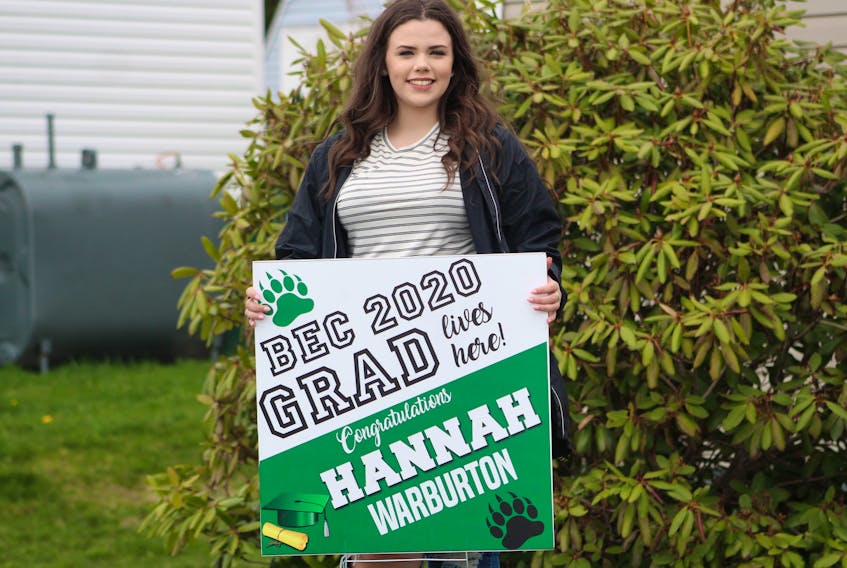 Hannah Warburton, 18, stands beside her Breton Education Centre graduation lawn sign outside of her Lingan home on May 21. Some parents of BEC graduates got the signs made for the Grade 12 students to celebrate since the restrictions on public gatherings in Nova Scotia enacted to limit the spread of COVID-19 have forced proms and safe grads to be cancelled. NICOLE SULLIVAN/CAPE BRETON POST  
