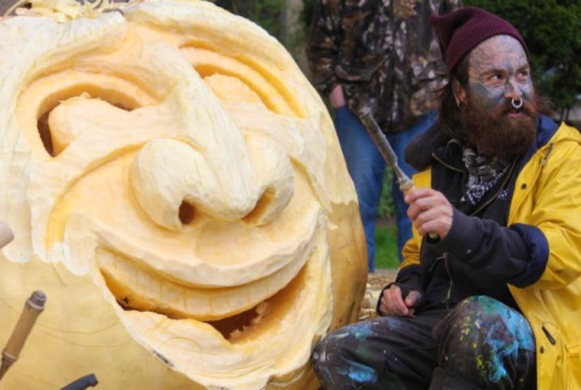Gordon Sparks works on his 1,051-pound pumpkin on Saturday morning. Sparks' jack-o'-lantern, from the Dill family farm in Windsor, will be on display until Halloween.