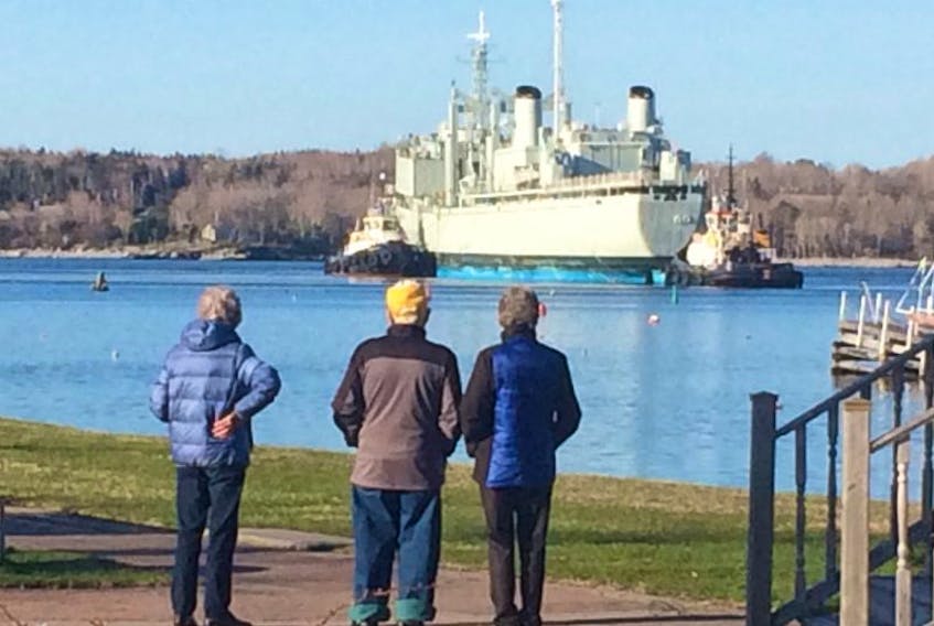 A group of people gather in Brooklyn early Friday morning to watch the former navy vessel, the Protecteur, slip into Liverpool Harbour.