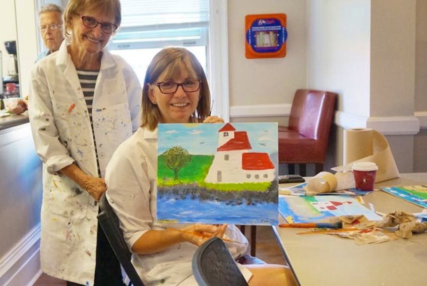 Gail Dyer and her daughter Cindy Dyer show the paintings they created at a Maud Lewis themed art workshop at an Astor Theatre fundraiser in Liverpool, N.S. July 22.