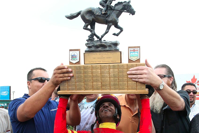 Jockey Rico Walcott holds up the Governor General's Trophy after winning the 85th Canadian Derby at Northlands Park on Aug. 16, 2014.