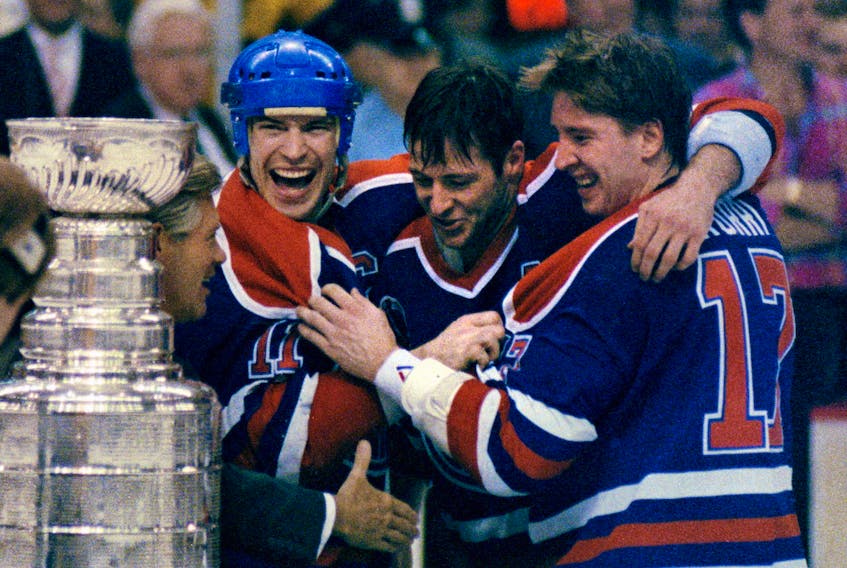 Left to right, Edmonton Oilers veterans team captain Mark Messier, Asst. captain Kevin Lowe, and Jari Kurri share the joy of them all winning their fifth Stanley Cup championship together. NHL commissioner John Ziegler reaches in to shake their hands and then hand over the cup to Messier after the Oilers beat the Boston Bruins in five games on May 24, 1990. 
