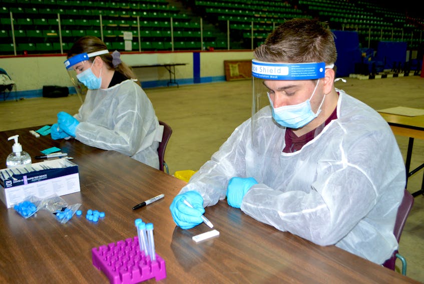 Corey Hanson of Albert Bridge and Michaela Berger of Sydney, volunteers at the community testing site at the Canada Games Complex at Cape Breton University, process rapid COVID-19 tests on Thursday. Sharon Montgomery-Dupe/Cape Breton Post