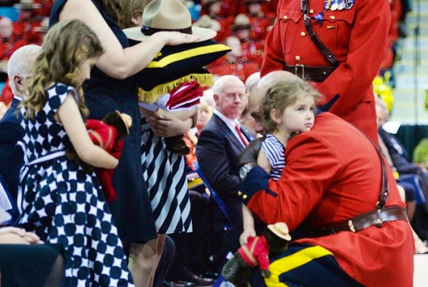 RCMP Commissioner Bob Paulson (right) hugs Const. Douglas Larche's daughter Alexa after presenting the slain RCMP officer's Stetson to widow Nadine (left) as her other daughters Lauren and Mia look on at a regimental funeral for the three slain officers in Moncton, N.B., Tuesday, June 10, 2014.&nbsp;