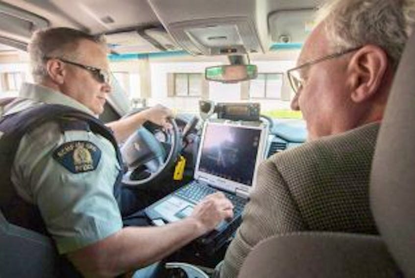 ['RCMP Cst. Chris Gunn explains the various pieces of equipment inside his patrol car to premier Wade MacLauchlan before heading to a checkstop in Queens County.&nbsp;']