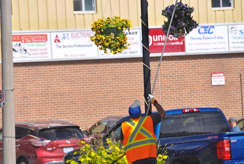A worker with the City of Corner Brook waters the hanging flower baskets along West Street on Wednesday, July 23.