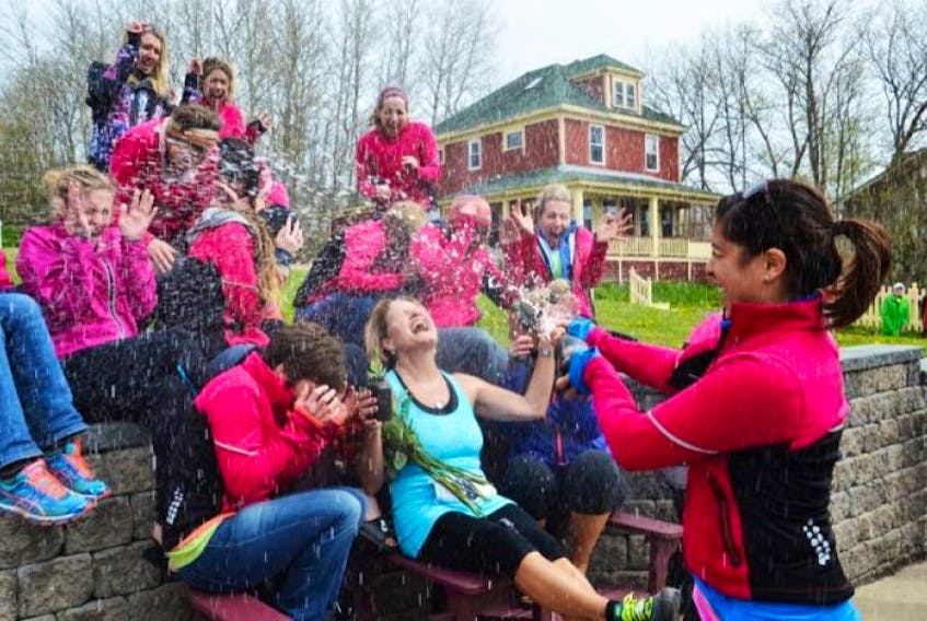 Hailee Campbell, a member of team Can’t Touch This, sprays a bottle of champagne over Kaye Toms and her fellow teammates after Toms completed the final leg of the Cabot Trail Relay Race in Baddeck on Sunday. After two decades of competing in the relay, Toms is moving on to new adventures.