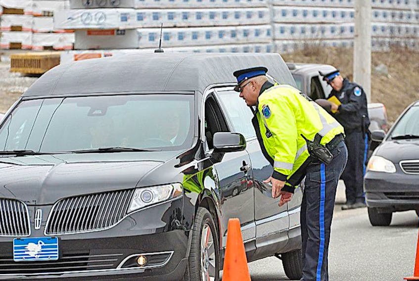 Const. John Goss of the Royal Newfoundland Constabulary talks with the driver of a hearse during a Canada Road Safety Week traffic checkpoint Tuesday morning on Riverside Drive. RNC Const. Keith Bursey can be seen checking another vehicle in the distance. <br />Diane Crocker/The Western Star