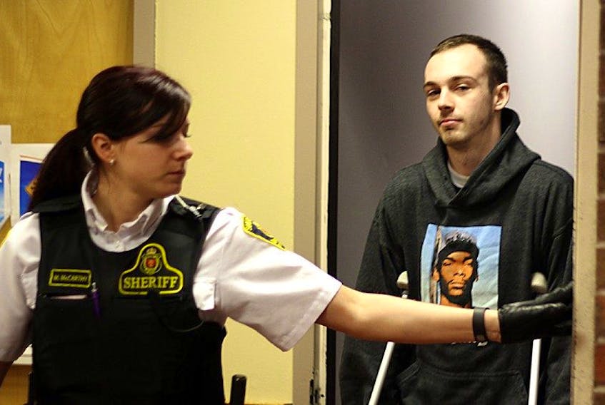 Tara Bradbury/The Telegram<br />Robert Mills, 22, is escorted into provincial court in shackles and on crutches Monday morning, in connection with a serious assault on a 21-year-old man at a house party in the Southlands area of St. John’s last weekend.