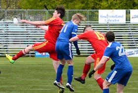 Players from Holy Cross players (in red) and Paradise  are seen in action during the 2018 Challenge Cup provincial senior men’s soccer play. — File photo