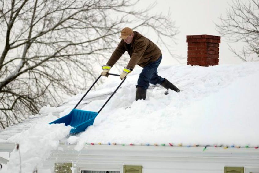 Roger Deveau of Charlottetown cleans the snow off the roof of his house Monday. The Island has been hit with heavy snowfalls this month and all that snow adds a &nbsp;lot of extra weight to roofs so it is a good idea to remove the snow, experts say.