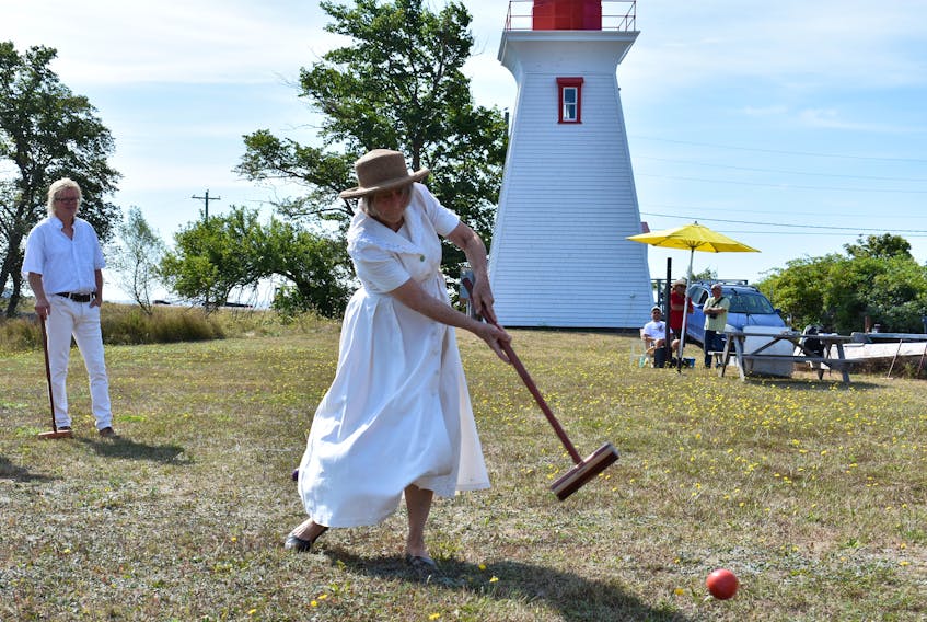 Linda Gilbert swings big during an opening match of Victoria’s annual croquet tournament while opponent Caspar Geurts watches in the background.