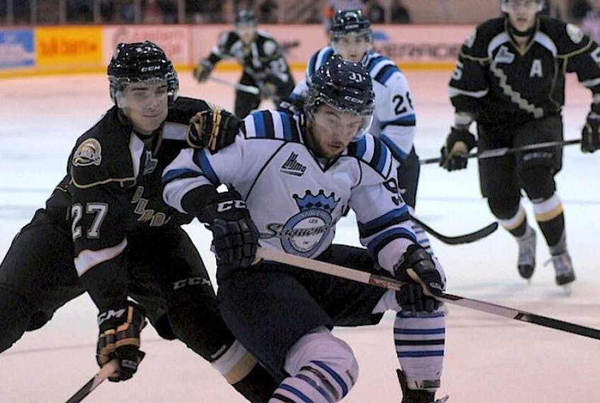Former teammates Ryan Graves, left, and Victor Provencher battle for a loose puck Saturday in Charlottetown.
