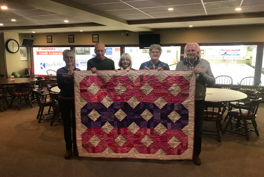 Sackville’s Curl for Cancer committee members, l-r, Sheila Parker, Alan Johnson, Debbie Stewart, Greta Patterson and Wayne Harper hold up a quilt donated by the Sackville Quilter's Guilt, which will be raffled during the event to raise funds.