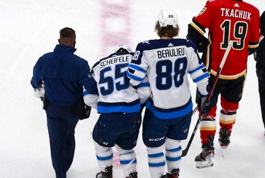 Jets forward Mark Scheifele is helped off of the ice by Nathan Beaulieu after a hard hit against the Calgary Flames in Game One of their playoff series last night. 