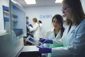 Hoda Rajabi (background) and Nicole Fahner (foreground) prepare to load a flow cell with environmental DNA into the NovaSeq 6000 DNA sequencing instrument at the eDNAtec lab in St. John's.
