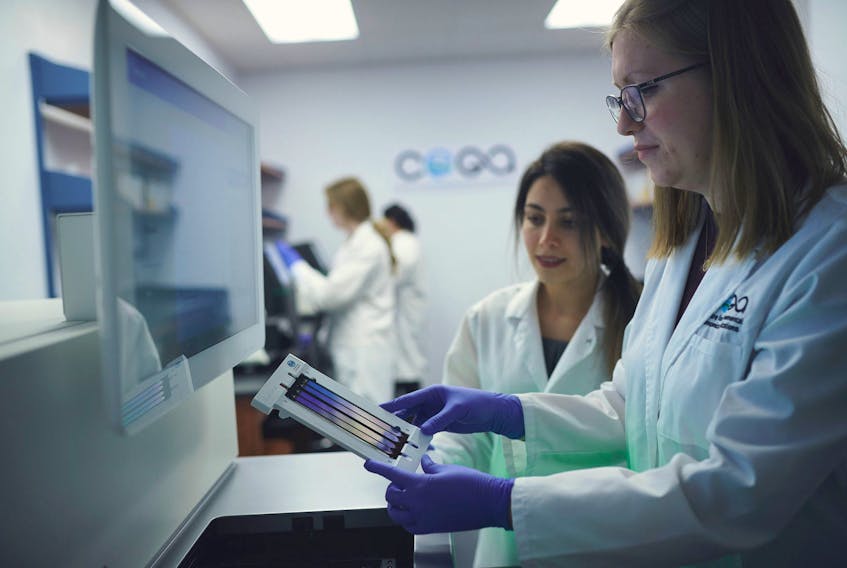Hoda Rajabi (background) and Nicole Fahner (foreground) prepare to load a flow cell with environmental DNA into the NovaSeq 6000 DNA sequencing instrument at the eDNAtec lab in St. John's.
