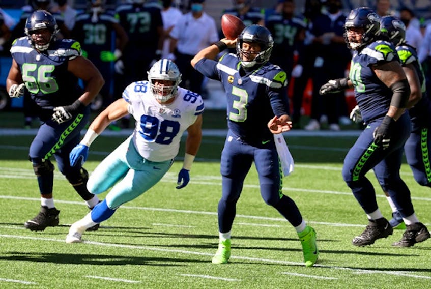 Russell Wilson  of the Seattle Seahawks looks to pass against the Dallas Cowboys during the second quarter in the game at CenturyLink Field on September 27, 2020 in Seattle, Washington. 