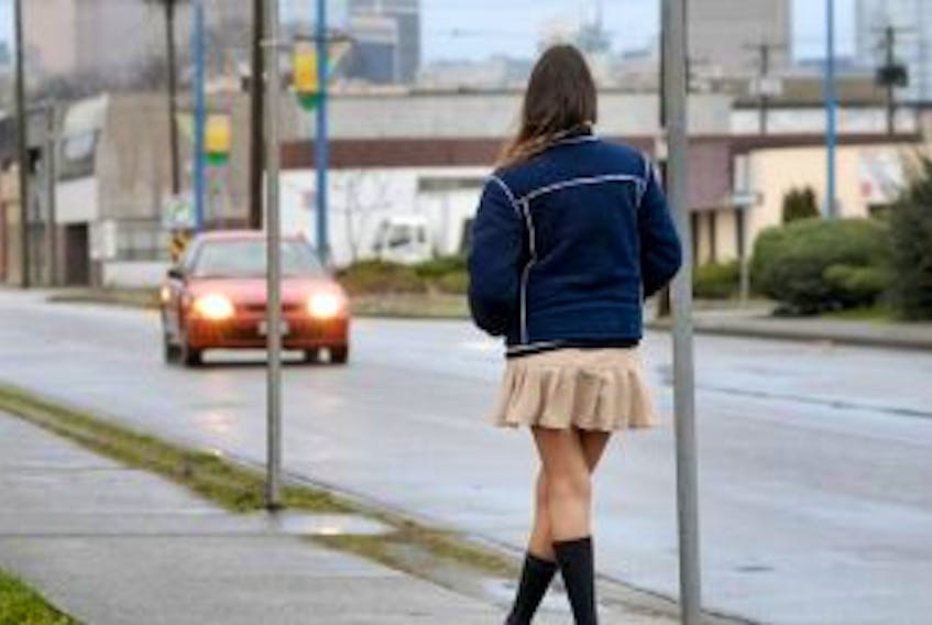 ["A sex worker stands on a street corner in Vancouver's Downtown Eastside."]