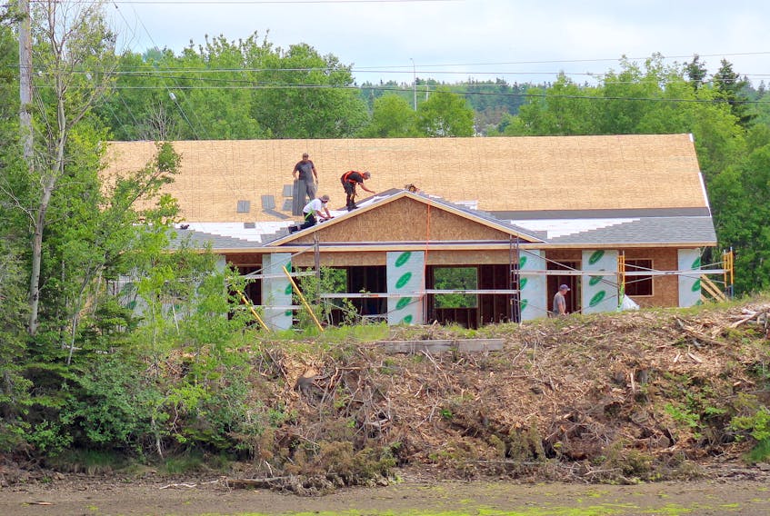 Contractors shingle the roof of a duplex that is being built along Sydney harbour near the bridge on Keltic Drive. Two duplexes are nearing completion as part the Arial Estates development. According to a sign on the site, each unit features two bedrooms, two bathrooms and a heated garage. Chris Connors/Cape Breton Post