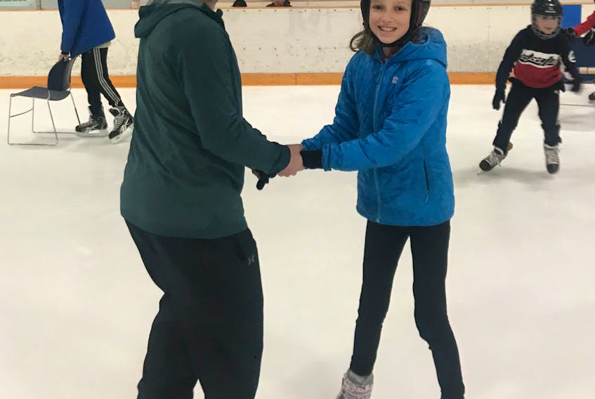 Mr. Ryley Nadon helps Lily Smallwood during the school ice skating party sponsored by the Knights of Columbus.