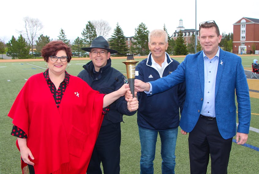Special Olympics Canada 2018 Summer Games opening and closing ceremonies chair Mary Farrell (left) and John Pellerin of the Law Enforcement Torch Run, along with Games' organizing committee co-chairs Carl Chisholm and Marc Champoux, proudly hold the torch after the opening of the Eastern Highlands Special Olympics regional competition May 17 on the St. F.X. campus in Antigonish. Whether the Games are staged in Vancouver or Antigonish, the Torch Run is a key part of the celebration. Corey LeBlanc