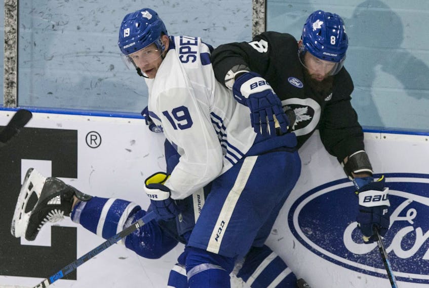 Jason Spezza takes Jake Muzzin into the boards as the Maple Leafs opened camp in Toronto on Monday.