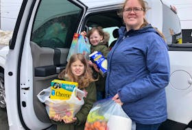 Paradise resident Vicki Collins with her daughters, Anna, 8, (front) and Audrey, 6, on Wednesday morning. While the photo was being taken, a friend dropped by to donate bags of groceries. JOE GIBBONS/THE TELEGRAM