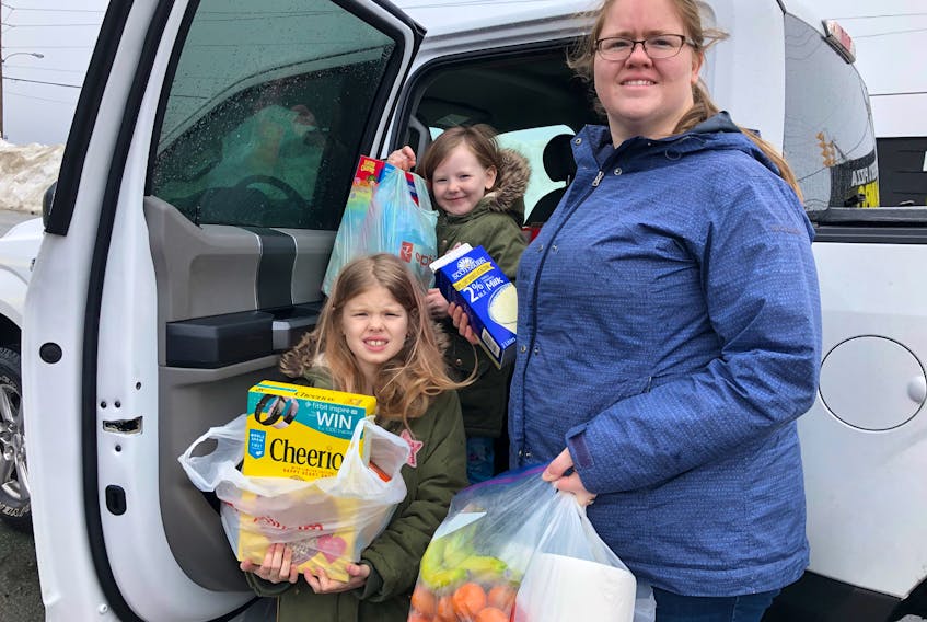 Paradise resident Vicki Collins with her daughters, Anna, 8, (front) and Audrey, 6, on Wednesday morning. While the photo was being taken, a friend dropped by to donate bags of groceries. JOE GIBBONS/THE TELEGRAM