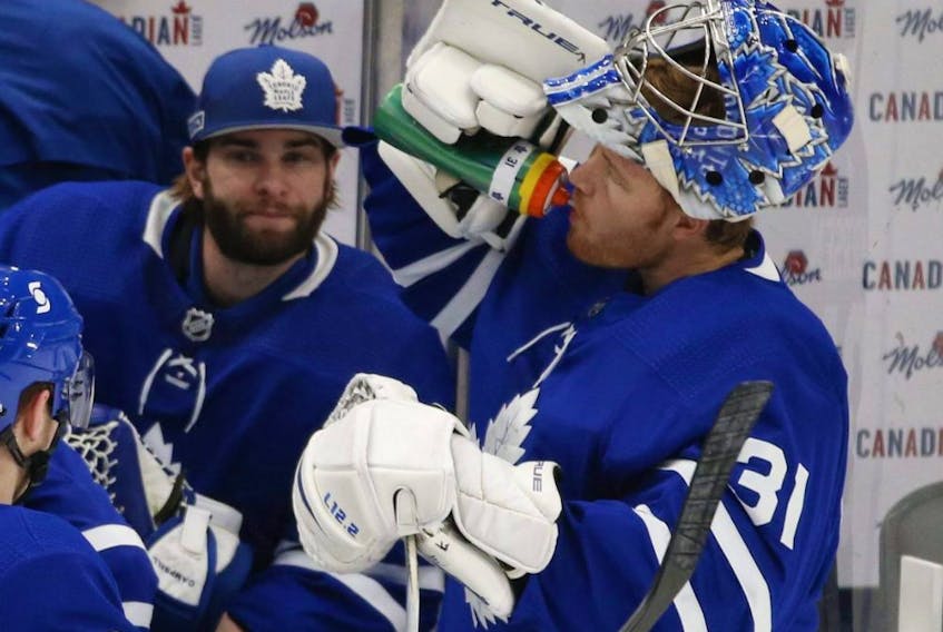 Toronto Maple Leafs goaltender Jack Campbell is on the bench while teammate Frederik Andersen gets a beverage during a break in the action during the first period on Jan. 18, 2021.