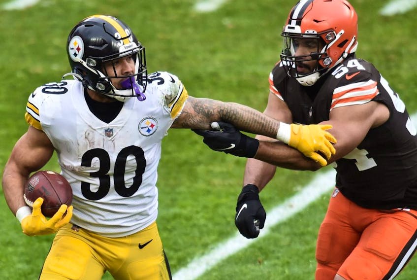 Pittsburgh Steelers running back James Conner (left) runs with the ball as Cleveland Browns defensive end Olivier Vernon defends on Jan. 3, 2021 at FirstEnergy Stadium.