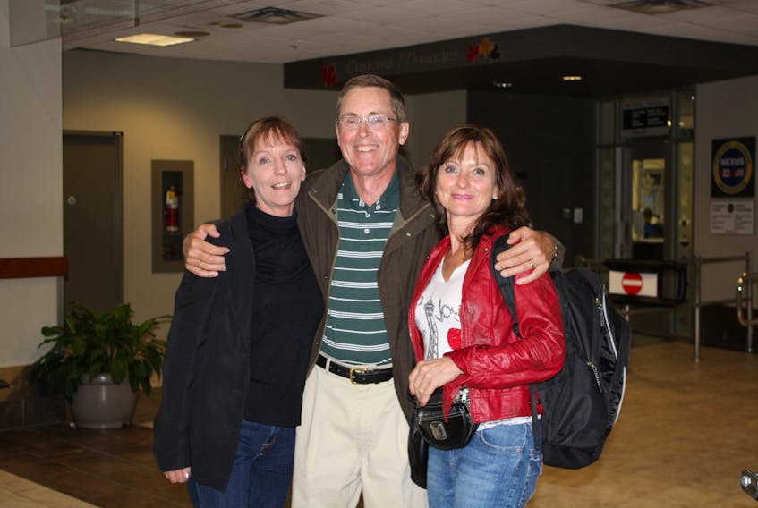 Gordon McMillan is all smiles as he poses with his half-sister Mary Morris, left, and his wife, Lyn, just moments after Morris stepped off a plane in Halifax and they met in person for the first time.