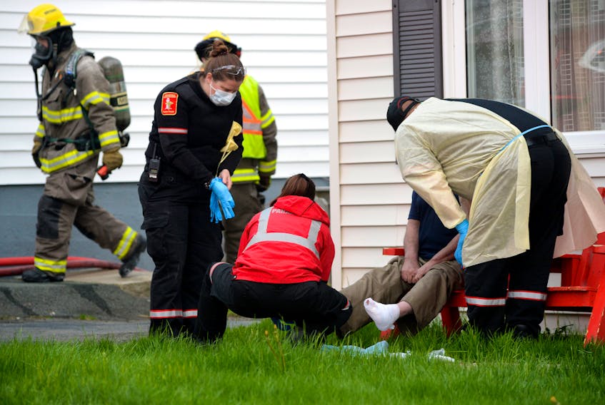 Paramedics treat an injured man following a house fire in St. John’s Wednesday night. Keith Gosse/The Telegram