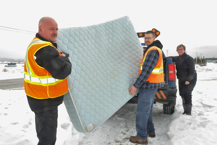 Michelle Cormier, right, chair for Aunt Jean’s Place Inc., looks on as Town of Stephenville Public Works Department employees, from left, Tony March and Wayde Smith, load a mattress donated by Hotel Stephenville. The shelter provides temporary housing for those in need. FRANK GALE/THE WESTERN STAR
