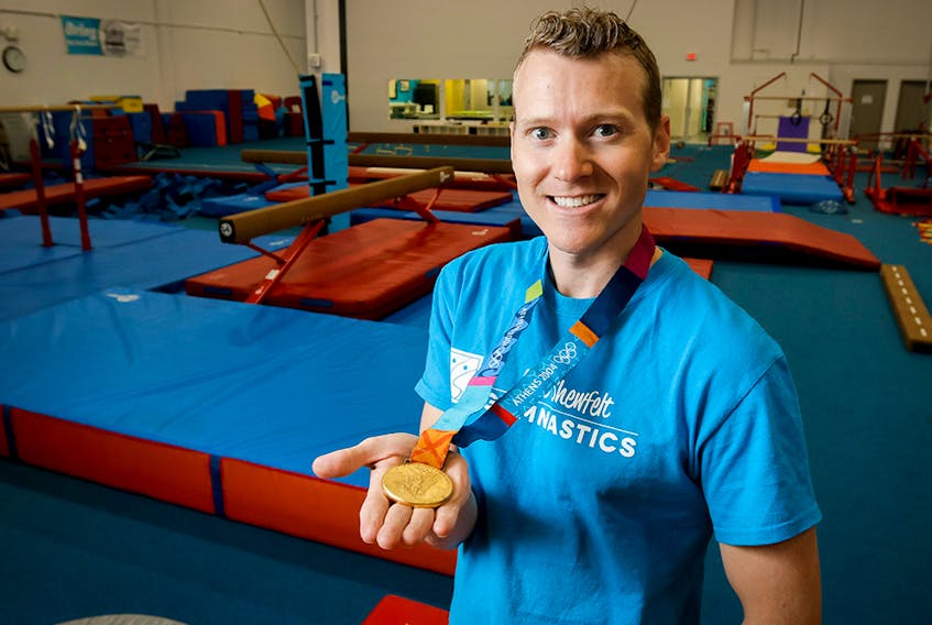  Kyle Shewfelt shows his Olympic gold medal at his gymnastics facility in southeast Calgary, Alta., on Thursday, Aug. 21, 2014.