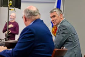 Premier Stephen McNeil speaks with Dr. Robert Strang, Nova Scotia's chief medical officer of health, at a COVID-19 news briefing in Halifax on Friday, Feb. 19, 2021. Sign language interpreter Richard Martell is seen in the background. It was McNeil's last briefing as premier. - Communications Nova Scotia