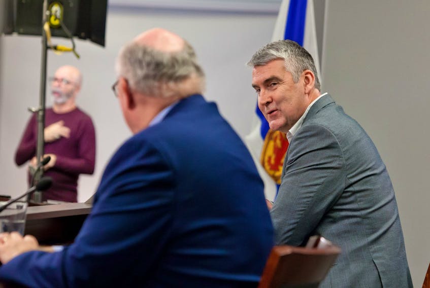 Premier Stephen McNeil speaks with Dr. Robert Strang, Nova Scotia's chief medical officer of health, at a COVID-19 news briefing in Halifax on Friday, Feb. 19, 2021. Sign language interpreter Richard Martell is seen in the background. It was McNeil's last briefing as premier. - Communications Nova Scotia