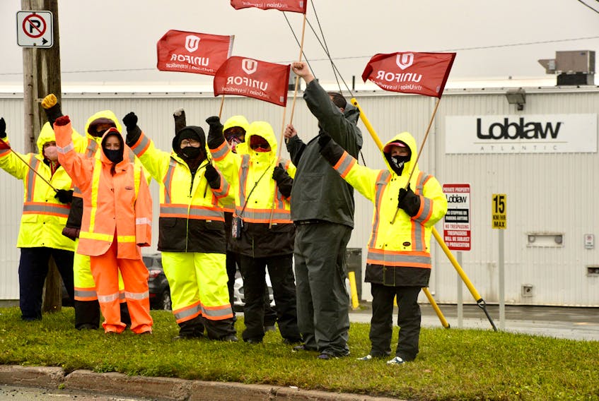 Striking Dominion workers wave the flag — literally and figuratively — after establishing a picket line at the Loblaw distribution centre in Donovan's Industrial Park Thursday morning. — Keith Gosse/The Telegram