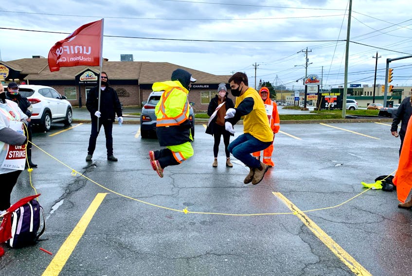 Striking Dominion workers Charlene Rodgers (left) and Jenna Martin (right) spin a rope as Tina Tricco and Michael Tucker jump during a fun moment at a demonstration at No Frills supermarket parking lot in Paradise Thursday morning. More than 100 Dominion workers turned out for the rally, in which they used the rope to form a "human chain of hope and solidarity." – ROSIE MULLALEY/THE TELEGRAM