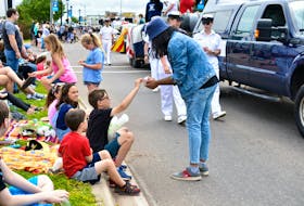 Sid Acharya from Feast Dinner Theatre cast ‘We Are the Champions,’ hands candy to Jack MacFarlane during the 2019 Lobster Carnival Parade. 