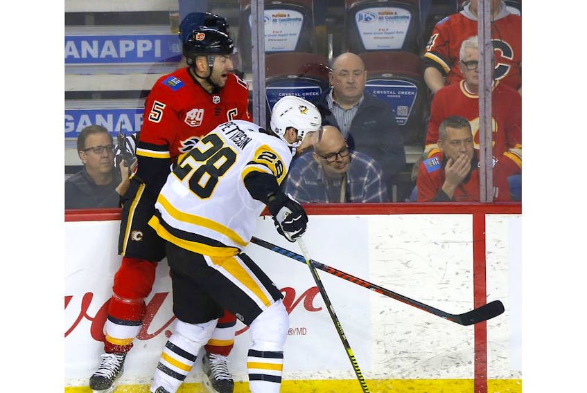 Calgary Flames defenceman Mark Giordano is taken hard into the boards by the Pittsburgh Penguins' Marcus Pettersson in second-period action at the Scotiabank Saddledome in Calgary on Tuesday. The Penguins won 4-1. Photo by Darren Makowichuk/Postmedia.